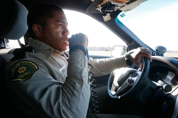Deputy talking on his radio while driving in a patrol vehicle