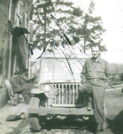 Andrew Garvy standing in front of a car with his right foot on the front bumper and his hands in his pocket