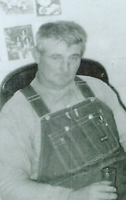 Chuck Benesh sitting in a chair after the war wearing overalls