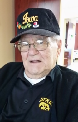 Bernard Hansen years later smiling wearing a Iowa Hawkeye polo and an Iowa hat