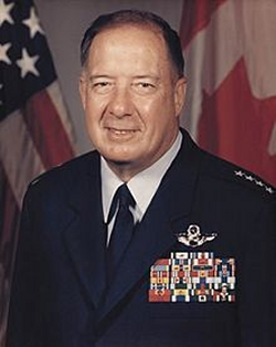 Charles Horner standing in front of 2 American Flags in his formal uniform with his miliitary stripes