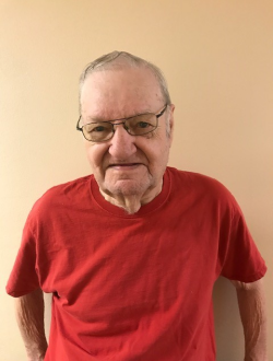 Donald Duder standing in front of a wall smiling years after the war