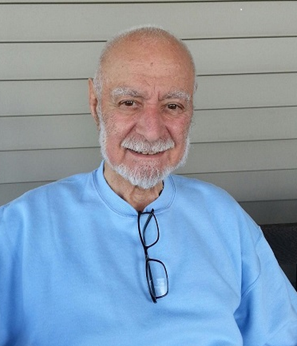 Ernest Nicholas years later sitting on a bench wearing a blue shirt