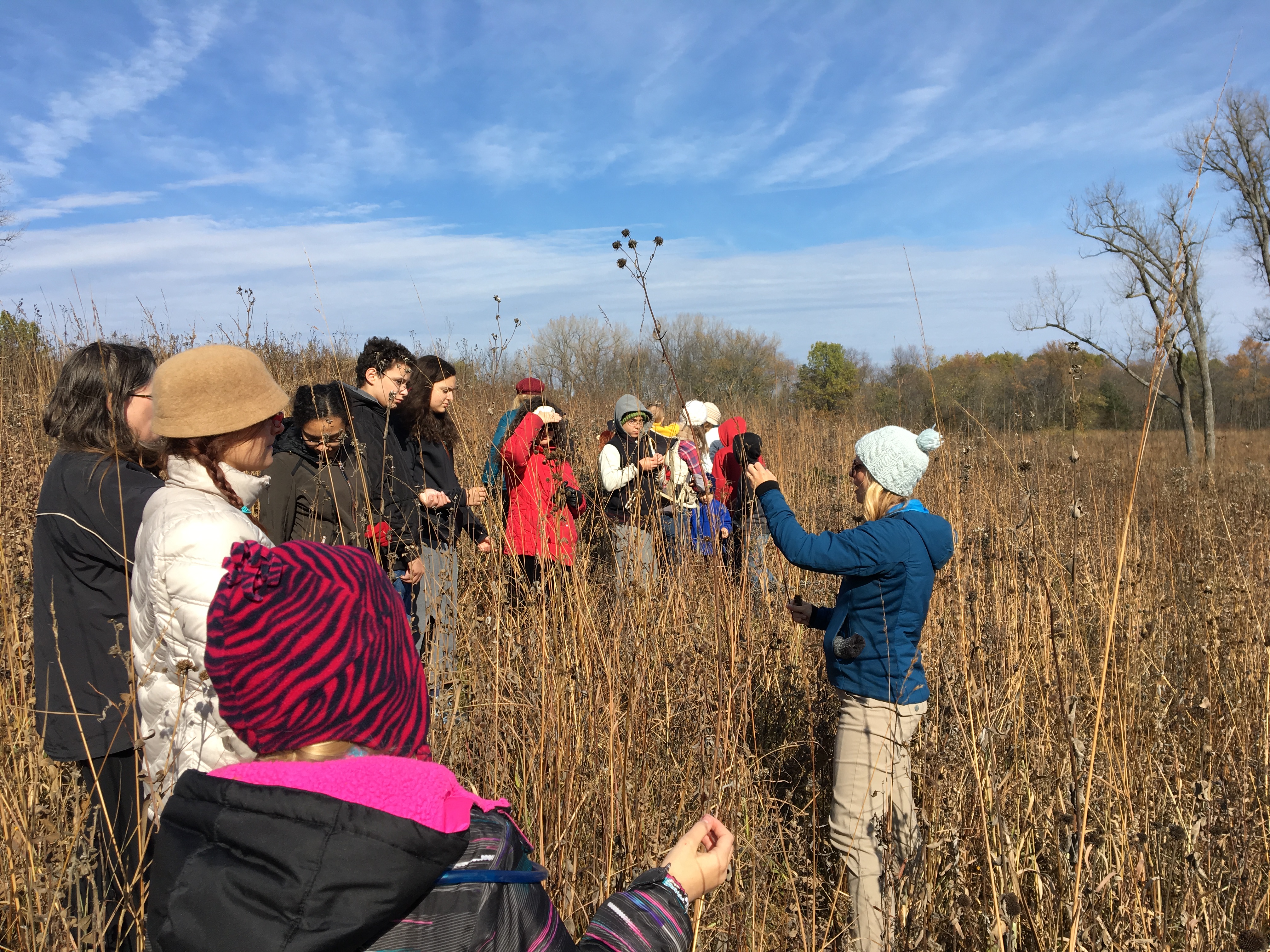 Naturalist talks to a group of people while exploring a prairie habitat in the fall.