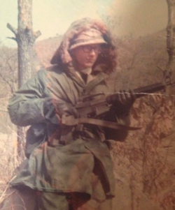 Jim Myrick wearing an Army winter jacket holding a rifle