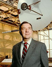 James Van-Allen standing in a museum wearing a suit