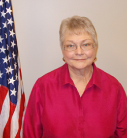 JoAnne Downes standing next to the American Flag years after the war