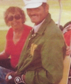 Orval Patten sitting in a golf cart wearing a green jacket and white hat