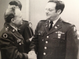 Donald Racheter shaking hands with a fellow soldier