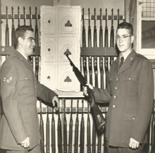 Robert Anciaux stangind with fellow soldier looking at guns