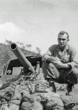 Robert Rohret kneeling next to a cannon