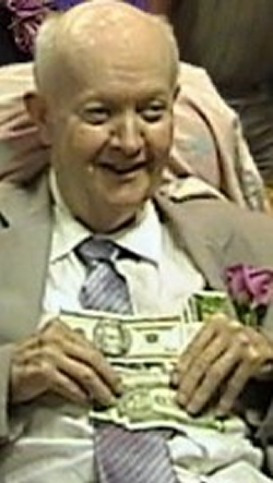 Thomas Fountain sitting in a chair wearing a suit with money laying on his stomach