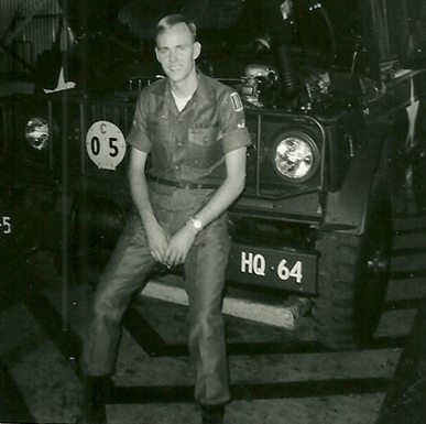 Thomas Cannon sitting on the front bumper of a jeep in the Panama Canal Zone in 1968